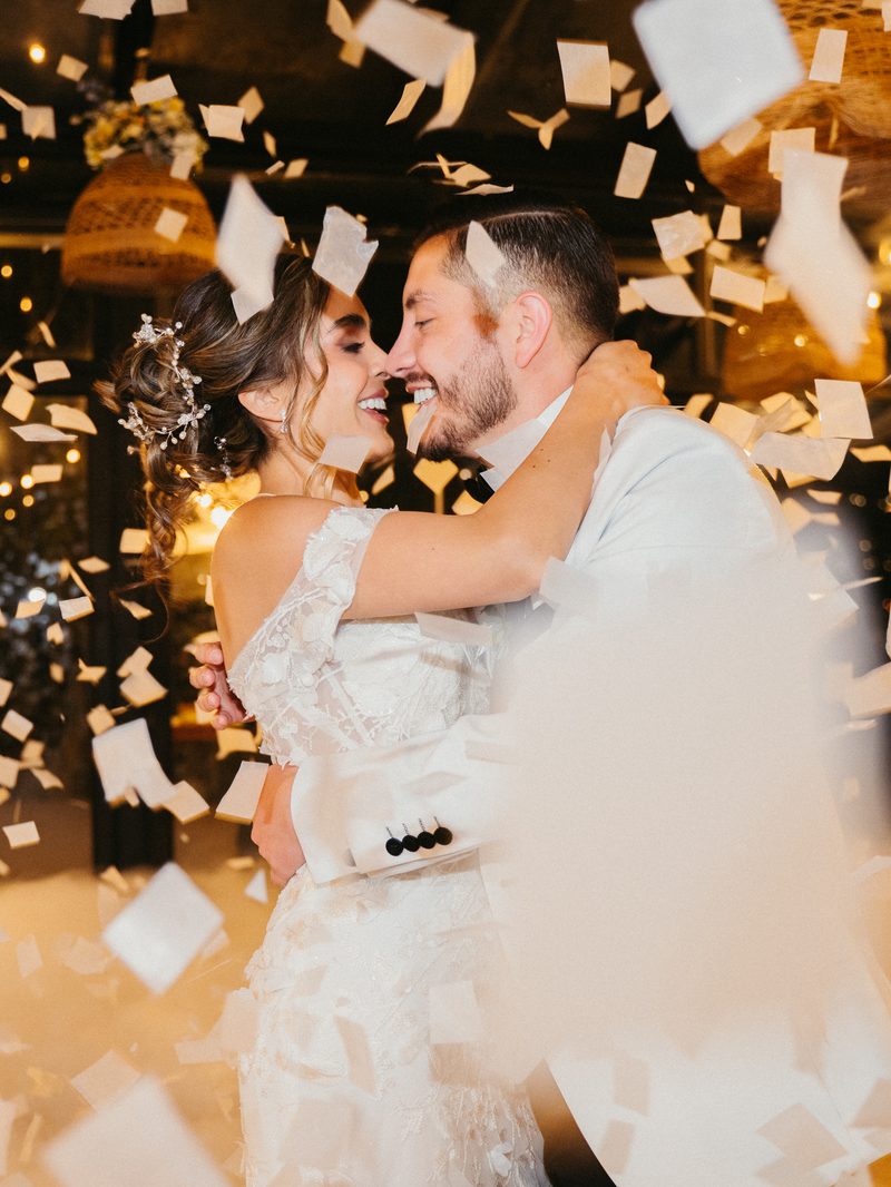 Novios besándose entre confeti, en blanco y negro