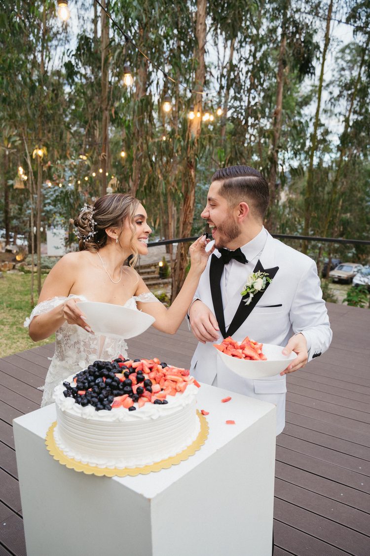 Novios compartiendo el pastel de bodas al aire libre