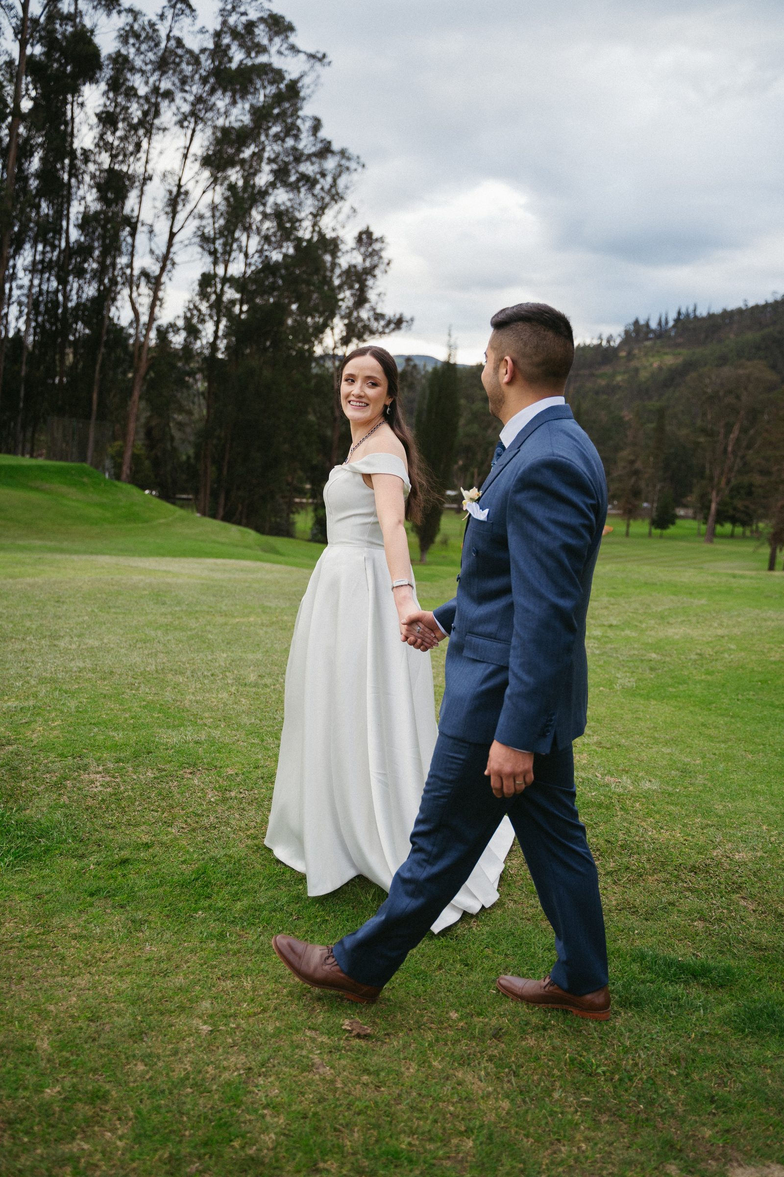Novios caminando de la mano por un campo verde en Cuenca