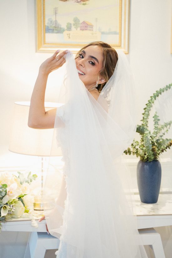 Novia sonriendo mientras juega con su velo