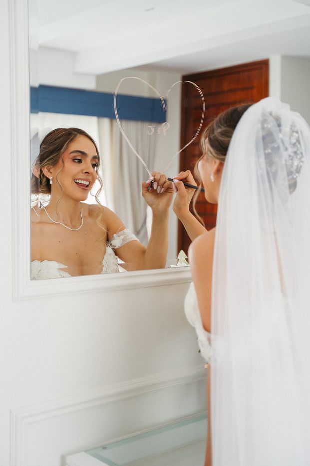 Novia dibujando un corazón en el espejo mientras se prepara