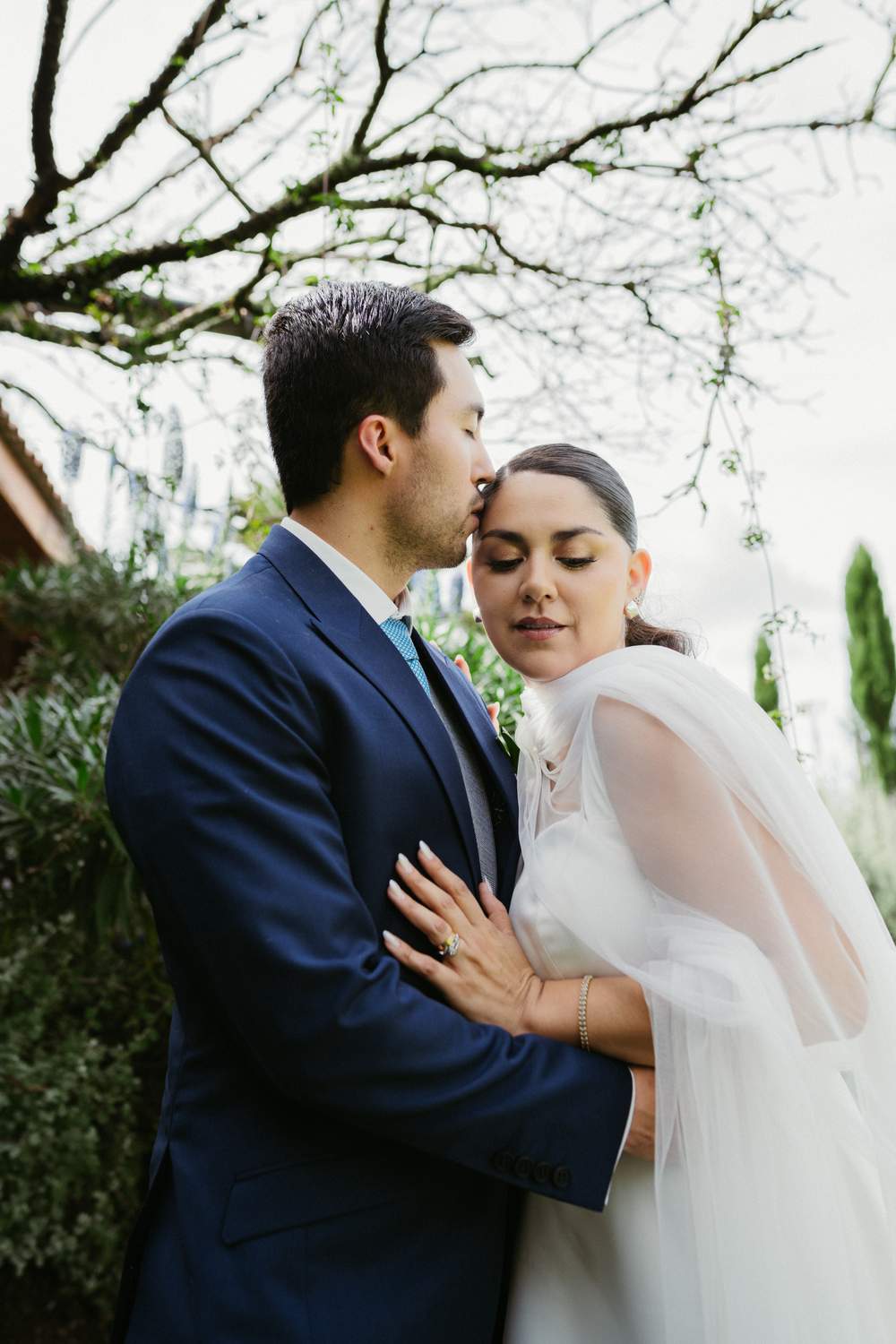 Pareja de novios en un momento íntimo bajo un árbol