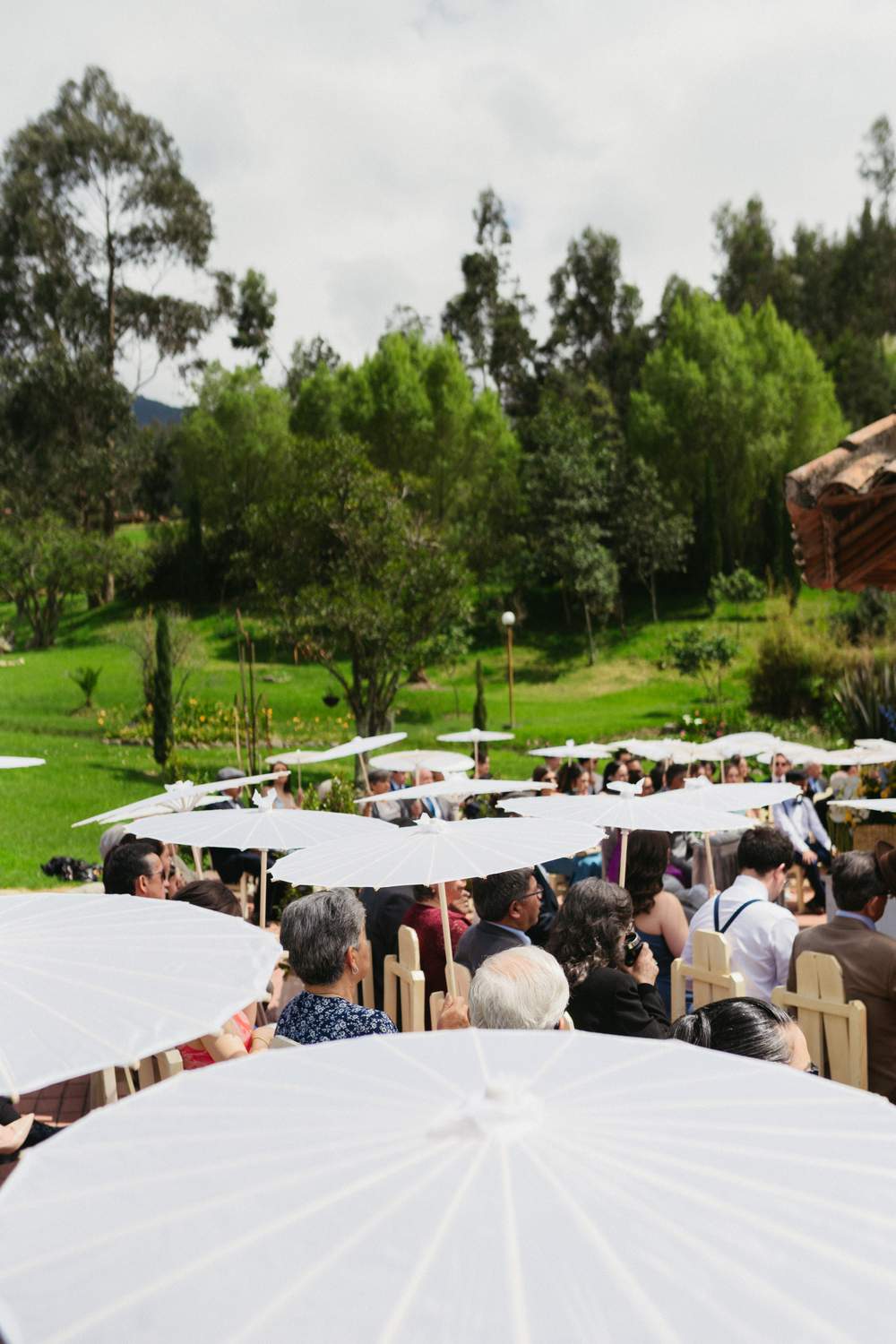 Invitados con sombrillas blancas durante la ceremonia al aire libre